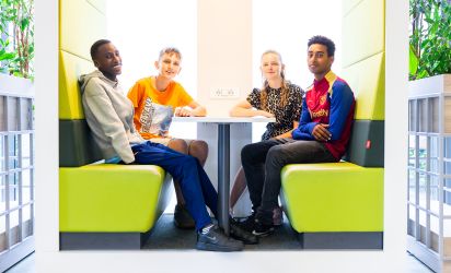 Leerling in gesprek met begeleiders in een rustige zithoek op school