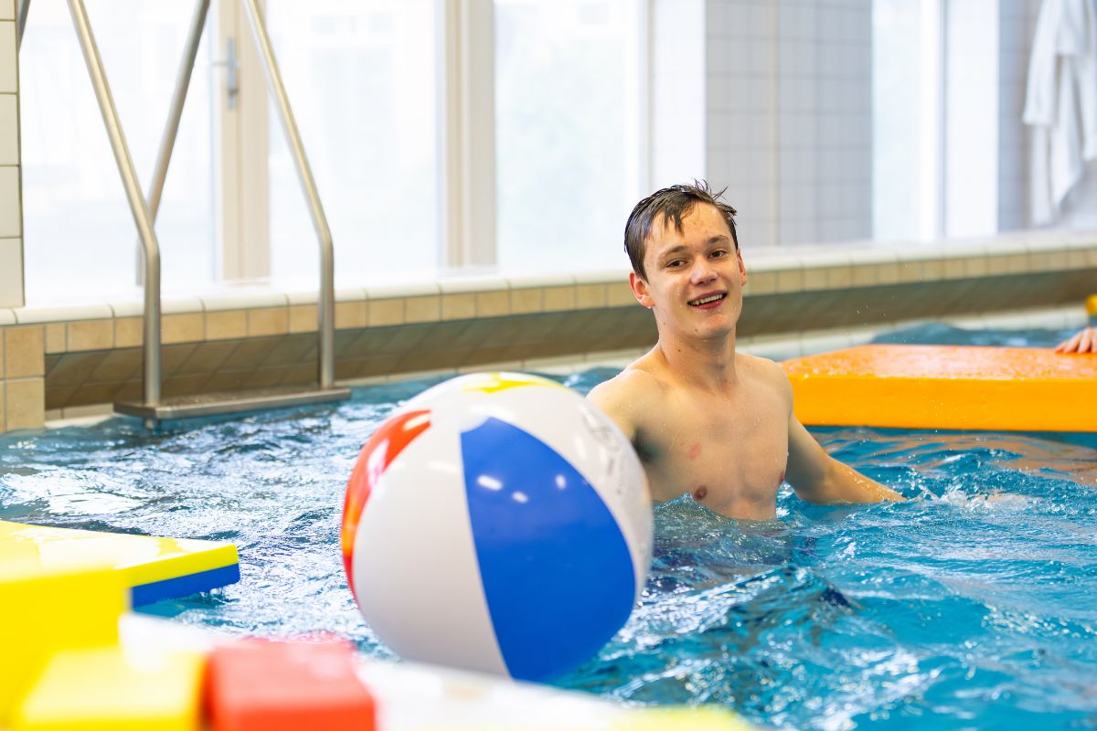 Bewegen en plezier in het water Leerling speelt met een grote strandbal tijdens een zwemactiviteit in het zwembad