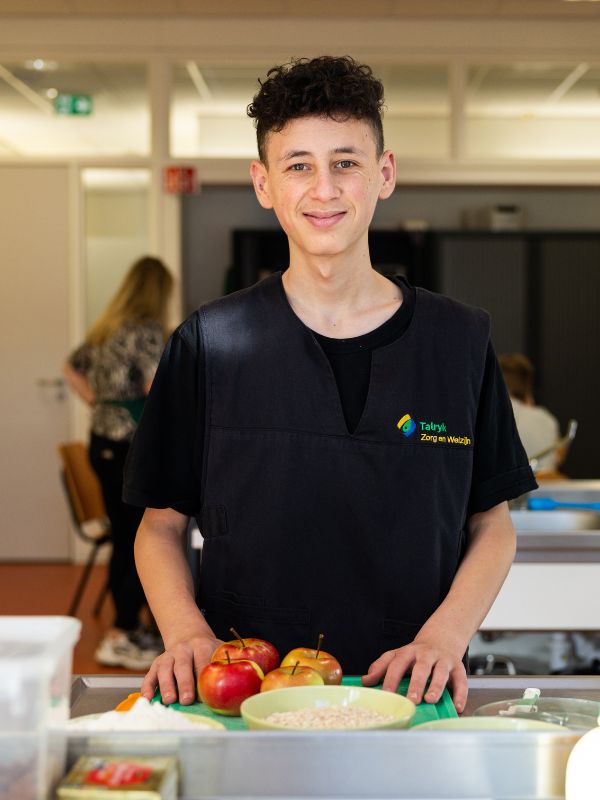 Leerling van Talryk Zorg & Werk bereidt fruit in praktijklokaal Leerling van Talryk Zorg & Werk staat in een praktijkkeuken en snijdt appels op een snijplank tijdens een kookles