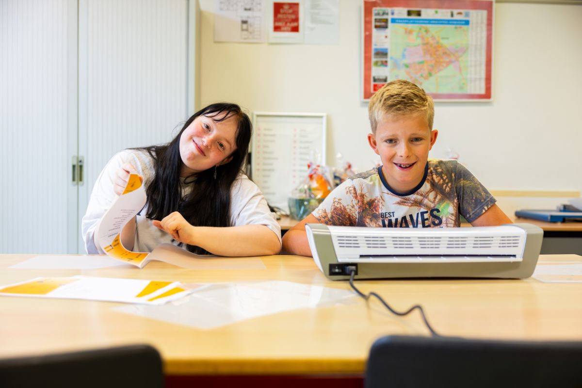 Twee leerlingen werken samen aan een opdracht aan een tafel in het klaslokaal