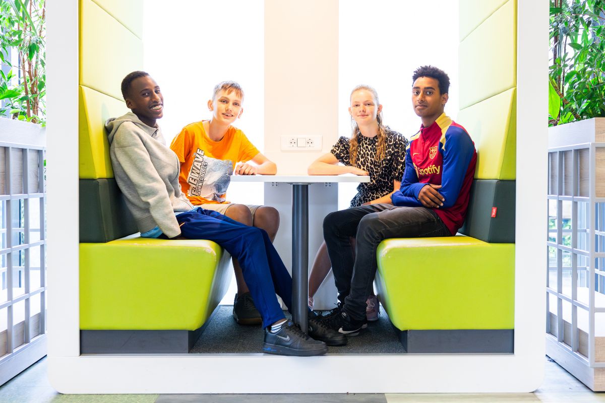 Vrienden en plezier Leerlingen zitten aan tafel tijdens een gesprek in een lichte ruimte op school