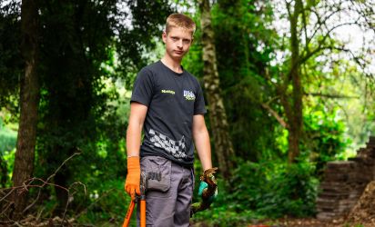 Leren werken in het groen Leerling van Talryk werkt in het groen en houdt tuingereedschap vast tijdens een praktijkles buiten