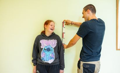 Medewerker van Talryk meet samen met een leerling haar lengte tijdens een begeleidingsmoment in de klas